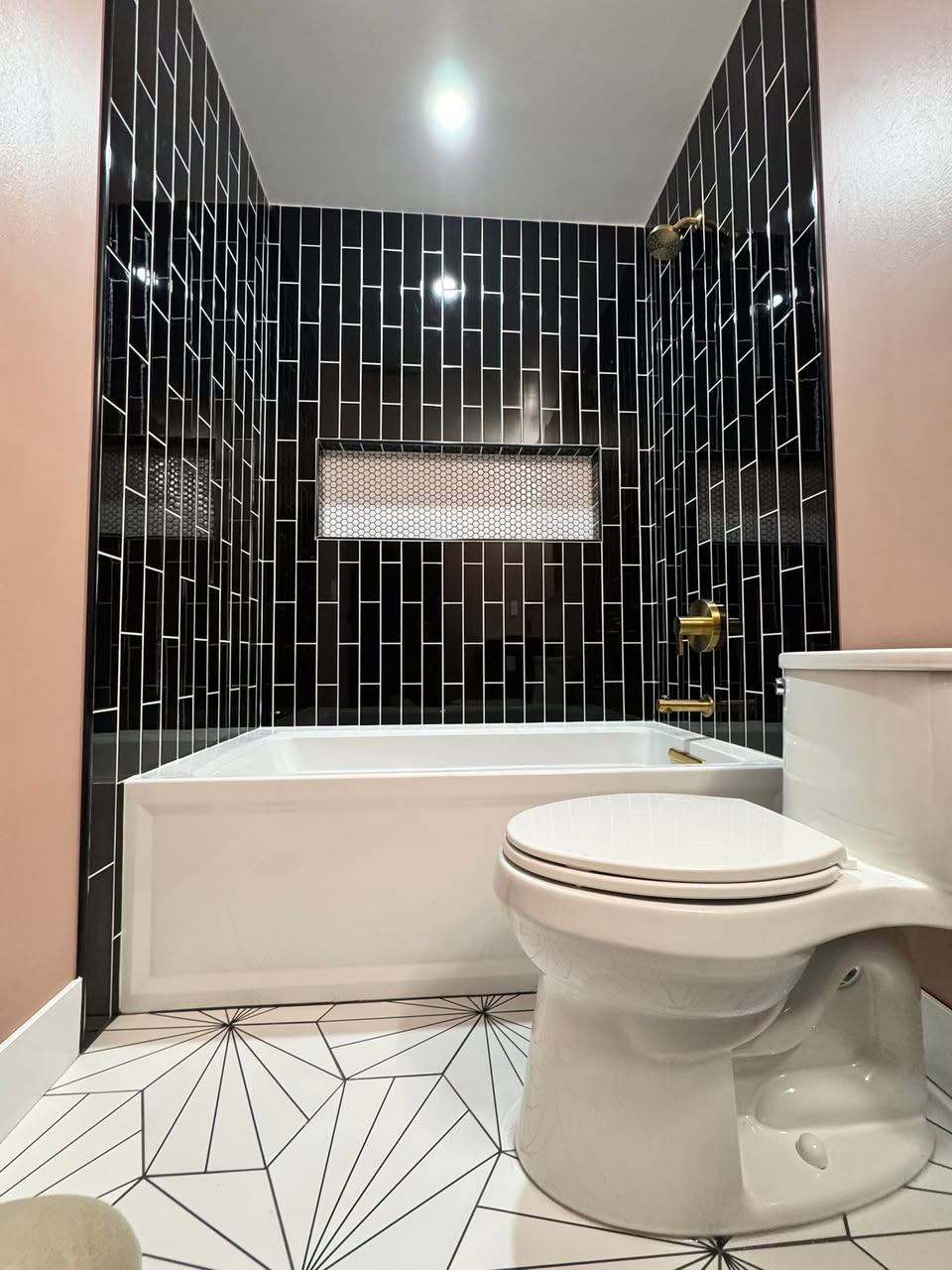 Bathroom finished in black tile with a built-in shower niche and a soaking tub