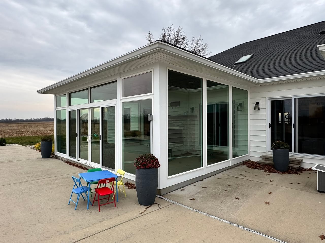 Four-season sunroom addition with floor-to-ceiling windows overlooking open ground