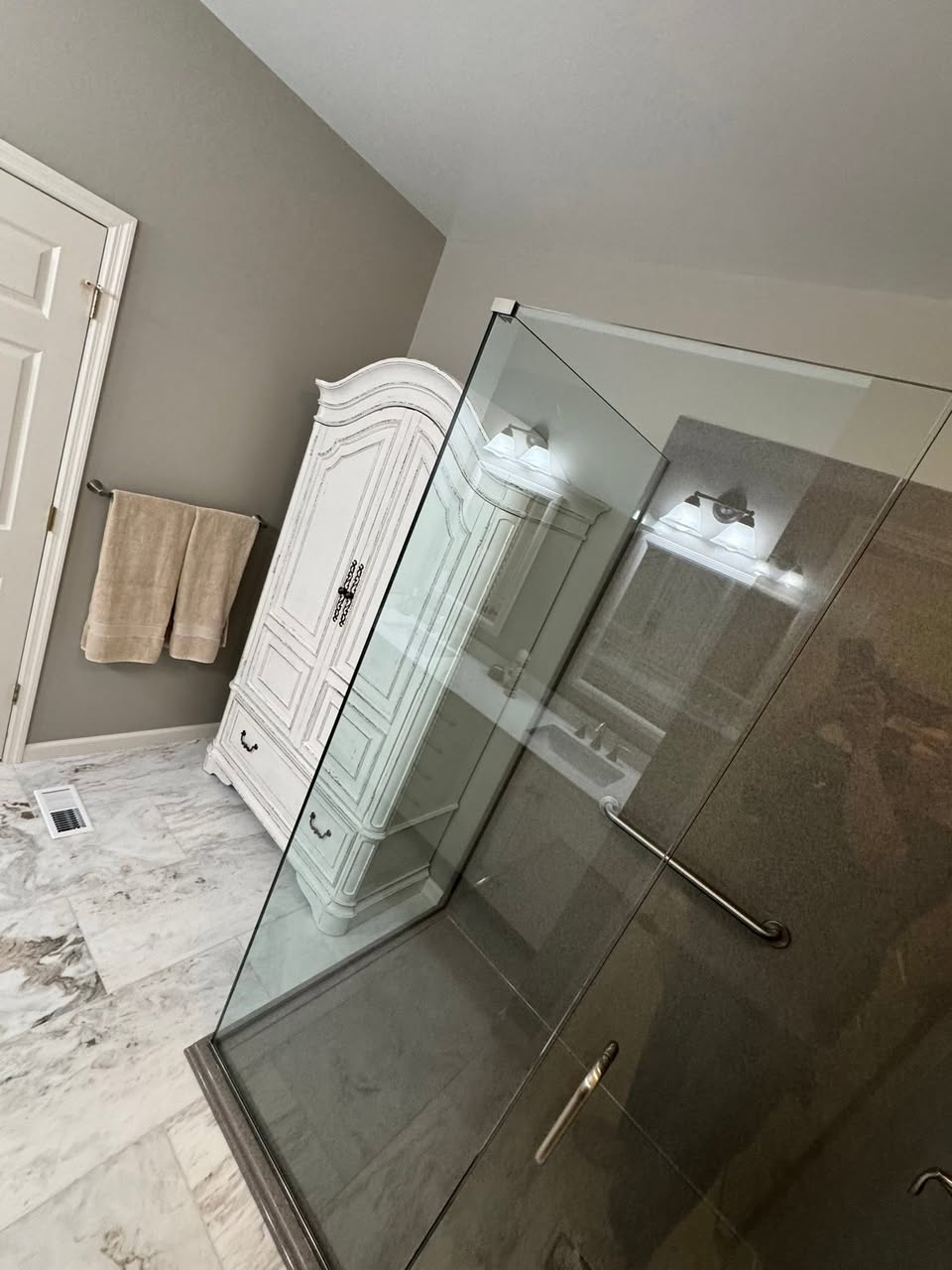 Master bathroom with a frameless glass shower enclosure and marble-look floor tile